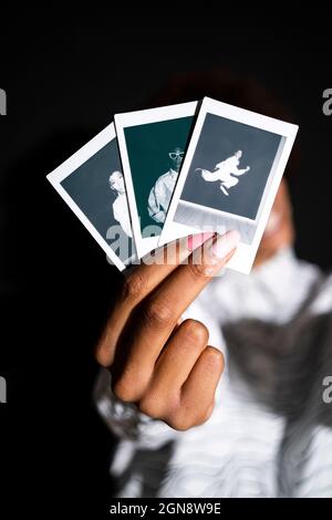 Woman showing polaroid photographs against black background