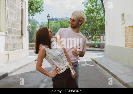 Young gay man and female friend looking at each other while standing on street Stock Photo