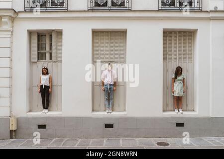 Young man and women looking down while standing in front of wall Stock Photo
