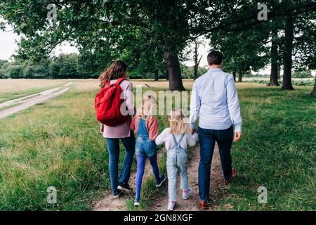 Daughters holding hands of parents while walking at park Stock Photo