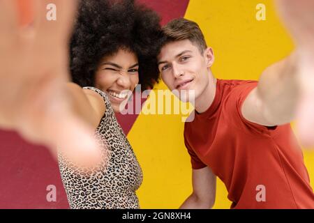Multi-ethnic young couple gesturing in front of wall Stock Photo