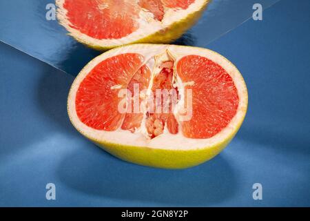 sliced mirrored yellow grapefruit on blue background Stock Photo