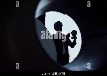 Businessman holding globe while standing in steel mill