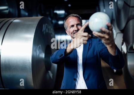 Businessman holding globe while standing at warehouse