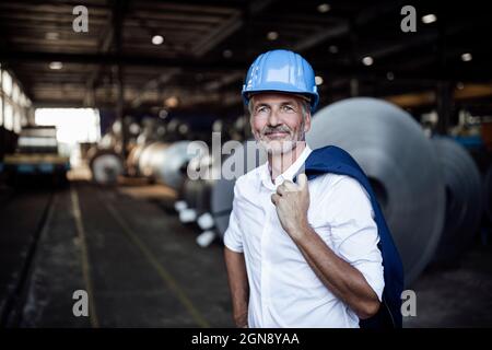 Male engineer with hardhat and blazer standing at distribution warehouse Stock Photo