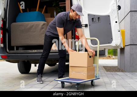 Male delivery person unloading boxes from moving van Stock Photo
