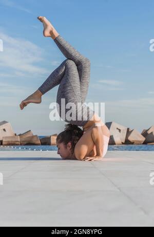 Woman practicing acroyoga on boardwalk by sea Stock Photo