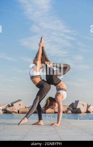 Young women practicing acroyoga on boardwalk Stock Photo