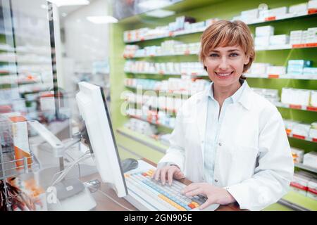 Smiling female pharmacist working on computer at medical store Stock Photo