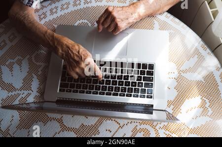 Elderly woman typing on laptop at home Stock Photo