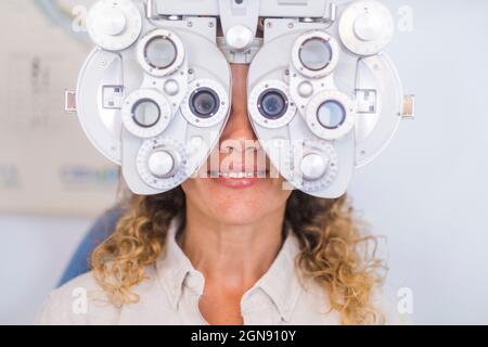 Smiling female patient examining eyesight through phoropter in medical clinic Stock Photo
