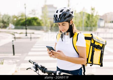 Delivery woman using mobile phone while standing on road Stock Photo