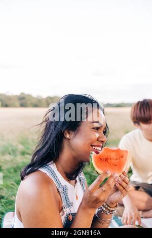 Smiling woman holding watermelon slice during picnic at park Stock Photo