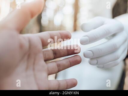 Hands of woman and robot touching Stock Photo