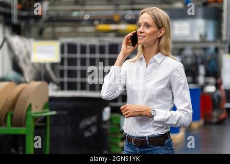 Female business professional talking on mobile phone at industry Stock Photo