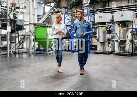 Business professionals discussing while walking in factory Stock Photo