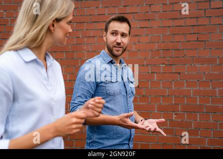 Businessman having discussion with colleague while standing by wall Stock Photo