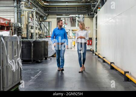 Business professionals discussing while walking in factory Stock Photo