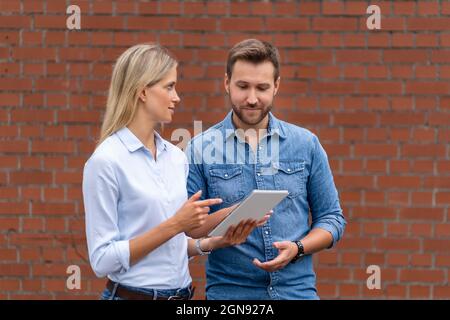 Business professionals using digital tablet in front of wall Stock Photo