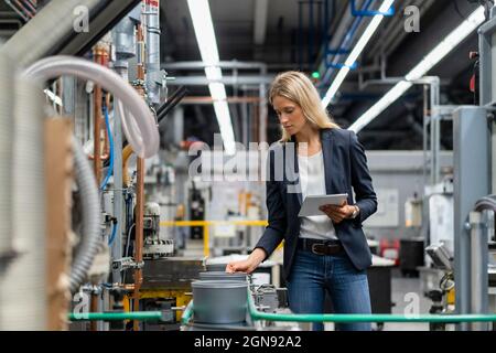 Female manager with digital tablet checking production line in factory Stock Photo