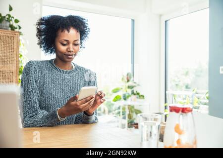 Female freelancer using smart phone at home office Stock Photo