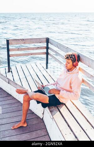 Young man using laptop on bench Stock Photo