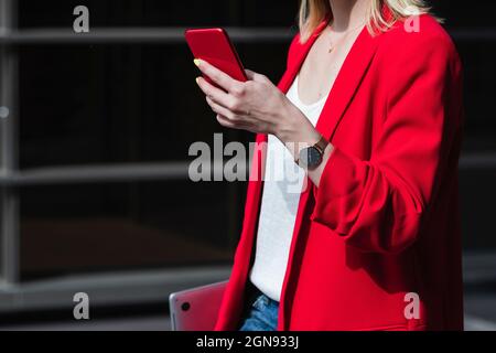 Businesswoman with laptop using smart phone during sunny day Stock Photo