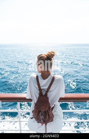 Woman wearing backpack looking at sea while standing in boat Stock Photo