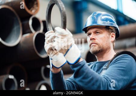 Male inspector with hardhat checking steel equipment in factory Stock Photo