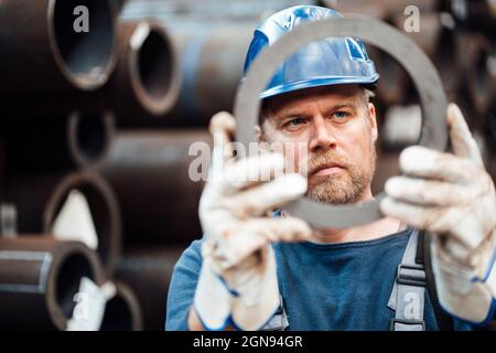 Male warehouse worker examining steel equipment in factory Stock Photo
