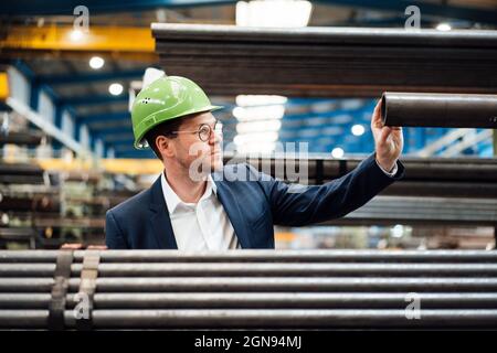 Smiling male professionals measuring pipe with caliper in industry Stock Photo