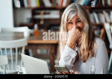 Female freelancer using laptop at table in cafe Stock Photo