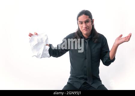 Man on white background. He towards camera showing he doesn't know the answer and has a torn sheet in his hand. dressed in formal clothes. White space Stock Photo