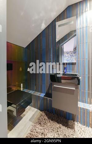 Wall hung toilet and small sink in corner in lavatory room with beige Stock Photo