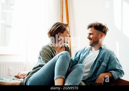 Happy couple embracing while sitting on bed at home Stock Photo