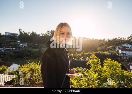 blonde woman with the mobile on a gazebo against sunset Stock Photo
