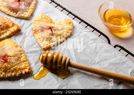 Studio shot of heart shaped cookies and two cups of coffee standing against black background Stock Photo
