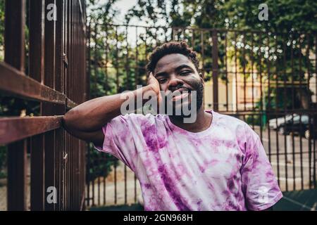 Smiling young man leaning on railing Stock Photo