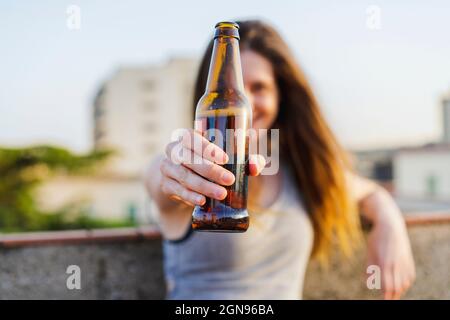 Young woman holding beer bottle at rooftop Stock Photo