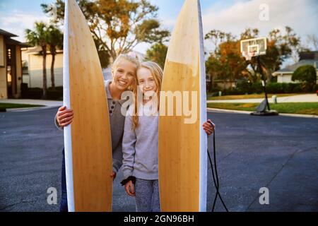 Smiling girls holding surfboards in public park Stock Photo