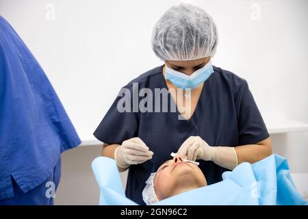 Surgeons performing eyelid surgery to anonymous patient Stock Photo