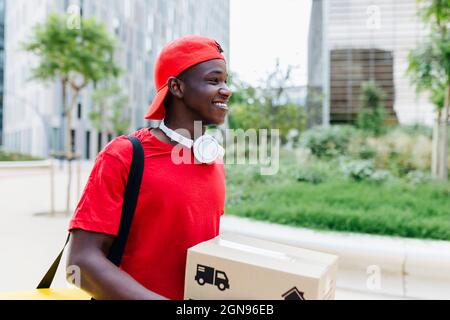 Happy young delivery man carrying box Stock Photo