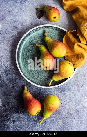 Organic ripe pears in ceramic bowl on rustic table Stock Photo