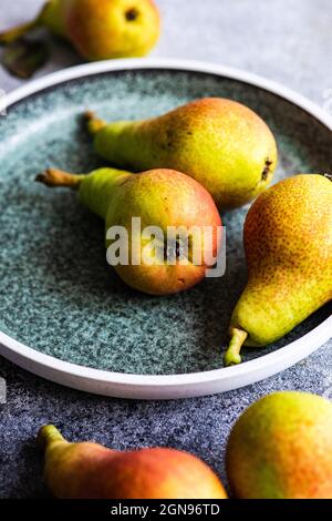 Organic ripe pears in ceramic bowl on rustic table Stock Photo