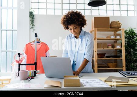 Female fashion designer using laptop while working at studio Stock Photo