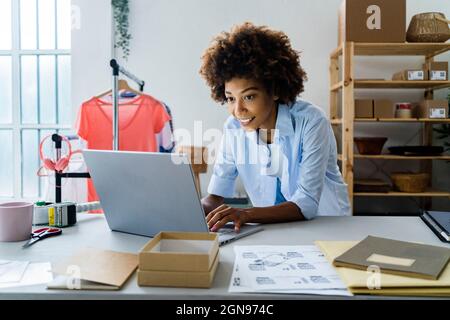 Young female fashion designer using laptop while leaning on desk at studio Stock Photo