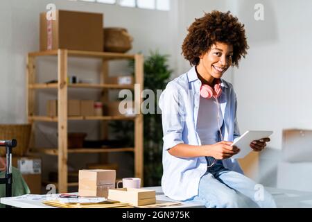 Female fashion designer using digital tablet while sitting on desk in studio Stock Photo