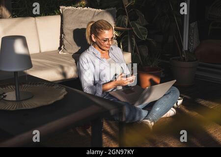 Female freelancer using mobile phone while working on terrace Stock Photo