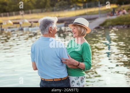 Cheerful senior couple looking at each other while standing by lake Stock Photo