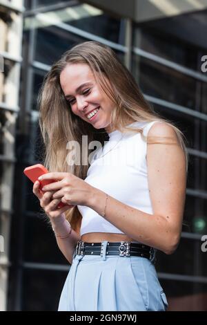 Happy blond businesswoman text messaging through mobile phone Stock Photo
